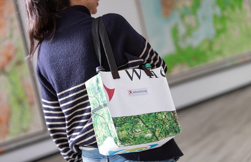 WhereGroup Mitarbeiterin mit WhereGroup-Recycling-Tasche mit Kartenmotiv und Logo