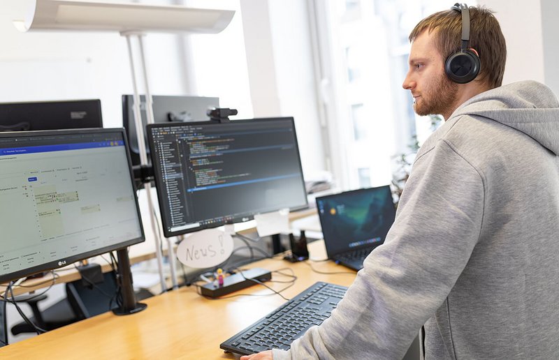 WhereGroup Softwareentwickler mit Kopfhörern bei konzentrierter GIS-Programmierung - praxisnahe Geo-IT-Entwicklung mit modernem Arbeitsplatz-Setup